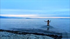 Naked woman greets the beauty of the sea Thumb